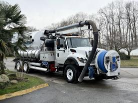 A 2013 International Workstar 7500 truck with a large vacuum tank and hoses attached for industrial cleaning purposes