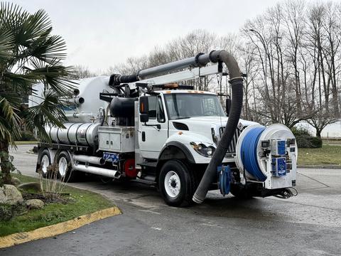 A 2013 International Workstar 7500 truck with a large vacuum tank and hoses attached for industrial cleaning purposes