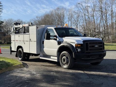 A 2009 Ford F-550 utility truck with a white exterior and equipment storage compartments on the side