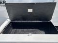 A black storage compartment with a hinged lid on a 2015 Ford F-750 truck chest is empty inside and features a round latch on the front