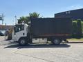 A 2016 Isuzu NPR-HD truck with a box-style cargo area parked on the side of a street