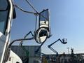 A 2008 Peterbilt 340 truck's side mirror reflecting the truck's front and surrounding equipment