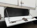 A 2014 International TerraStar with a storage compartment door propped open by chains and secured with a metal latch and handle