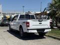 A white 2018 Ford F-150 pickup truck with a truck bed rack parked at an industrial location