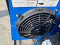 A close-up of a black cooling fan attached to a blue machine with warning labels next to it