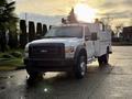 A 2010 Ford F-550 with a utility body and lights on the roof parked on a paved surface