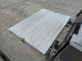 A flat loading ramp made of aluminum with a textured surface attached to the back of a 2022 International MV607 truck