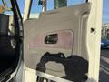 Interior door panel of a 2011 International 7500 featuring a textured handle and control panel in a gray and brown color scheme
