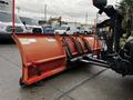 A 2009 Ford F-550 with an orange snow plow attachment mounted on the front