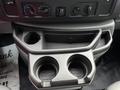 A gray center console of a 2017 Ford Econoline featuring two cup holders and control knobs for climate and audio settings