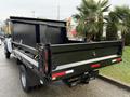 A 2017 Ford F-450 Super Duty truck with a flatbed and dump feature is parked displaying its rear bed and tailgate