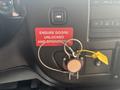 A 2020 Chevrolet Express dashboard showing a key ignition, a warning sign that says "ENSURE DOORS UNLOCKED AND OPERATIONAL" and a safety lock with a yellow tag labeled "FIRE"
