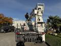 A white 2011 International 7500 bucket truck with an extended aerial lift arm and control panel in the rear section