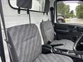 Interior view of a 2010 Suzuki Carry showing two gray cloth seats with patterned upholstery and a black steering wheel