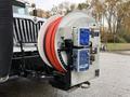 A 2014 International 7500 with a large mounted reel containing red hose and control panels for operating the equipment attached to the front of the vehicle