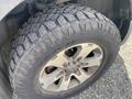 Close-up of a tire and rim from a 2014 Ford F-150 featuring a rugged tread pattern and shiny aluminum alloy rim