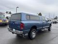 A blue 2006 Dodge Ram 2500 pickup truck with a cap on the bed and a four-wheel drive badge is parked with its rear facing the viewer