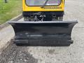 A black snowplow blade attached to a yellow Bombardier SW48 vehicle with the word Bombardier visible on the front