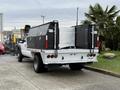 A white 2016 Ford F-550 Super Duty truck with a flatbed and black storage boxes on either side of the bed