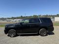 A black 2016 Chevrolet Tahoe parked on gravel with alloy wheels and tinted windows
