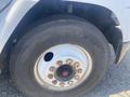 Close-up of a larger vehicle tire mounted on a steel wheel showing lug nuts and a noticeable hole on the tire's surface
