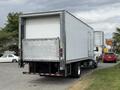 A 2019 Ford F-750 box truck with a white cargo area and rear liftgate parked, displaying its large wheels and trailer hitch