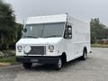 A white 2012 Ford E-450 Super Duty delivery truck with a boxy shape and large windshield parked on a paved surface
