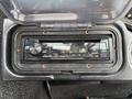 A Kenwood car stereo system displaying various control buttons and a digital screen for media playback