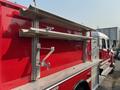 A red 1999 Freightliner FL80 fire truck showing metal storage racks and a shiny exterior with chrome detailing