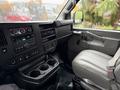 Interior of a 2021 Chevrolet Express featuring a dashboard with audio controls and air vents, a gray front seat, and a center console with cup holders