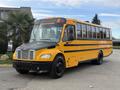 A yellow 2022 Freightliner B2 school bus with a black front grille and tires parked on a street