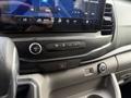 A close-up of the dashboard controls in a 2022 Ford Transit displaying buttons for volume and climate settings