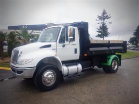A 2011 International 4300 truck featuring a white cab and a green and black flatbed bed with wooden flooring