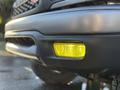 A close-up of the fog light on a 2004 Toyota Tacoma showing a yellow lens set into a black bumper