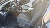 Interior of a 2018 Hyundai Sonata featuring fabric seats a steering wheel with controls and a center console with cup holders and various controls