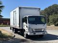 A 2022 Isuzu NQR truck with a large silver cargo box and a white cab parked on a street