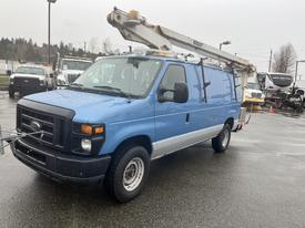 A blue 2009 Ford Econoline van with a utility ladder mounted on the roof and equipment on the front attached to the hitch