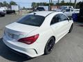 A 2014 Mercedes-Benz CLA-Class in white with a sleek design and black rims viewed from the rear three-quarter perspective