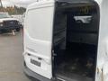 A 2017 Ford Transit Connect van with an open back door revealing a spacious cargo area with metal shelving and a mesh partition