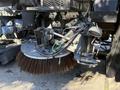 A 2012 Autocar XPERT street sweeper with a large rotating brush attachment designed for cleaning road surfaces