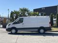 A white 2016 Ford Transit van with a roof rack and black accents parked on a paved surface