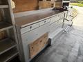 A metal workbench with multiple drawers and compartments inside a vehicle, featuring a flat surface and a clamp on the right side