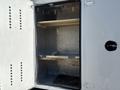 A white 2011 Ford F-550 truck with an open rear compartment featuring shelving and a wooden plank inside