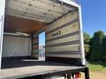 A 2022 Isuzu NQR truck with an empty cargo area featuring a wooden floor and metal walls with a door opening on one side
