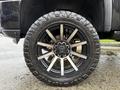 A close-up of a multi-spoke black and silver wheel with an aggressive off-road tire mounted on a 2022 GMC Sierra 3500HD