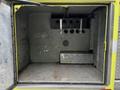 An empty cargo area of a 1995 Freightliner FLL086 featuring gray walls and compartments for storage with several round openings visible on the back panel