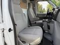 Interior of a 2013 Ford Econoline showing two gray upholstered front seats and a central console with cup holders