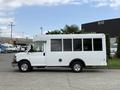 A 2013 Chevrolet Express bus in white with large windows and chrome wheels parked on a lot