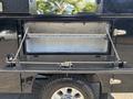 A 2022 Ford F-350 SD with an open truck bed toolbox featuring a hinged lid and chain supports