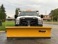 A 2013 Ford F-450 SD pickup truck with a yellow snow plow attached to the front